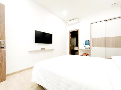 a white room with a bed and a tv at HERA HOSTEL in Chau Doc