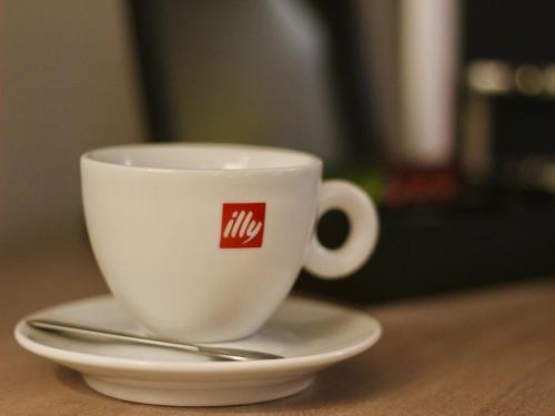 a white coffee cup on a saucer with a spoon at The Suffolk Hotel in Haverhill