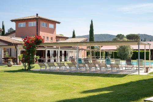 um grupo de cadeiras num relvado em frente a uma casa em Guadalupe Tuscany Resort em Braccagni