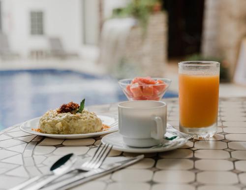 una mesa con un plato de comida y un vaso de zumo de naranja en Hotel Patrimonial by Greenfield, en Guayaquil