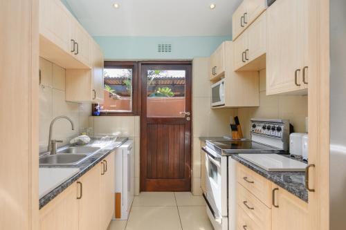 een keuken met houten kasten, een wastafel en een deur bij San Lameer Villa 2806 - 3 Bedroom Classic - 6 pax - San Lameer Rental Agency in Southbroom