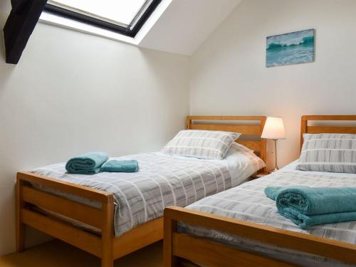 two twin beds in a room with a window at Barn Court Cottage in Washfield