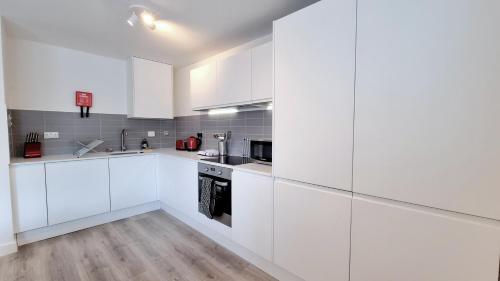 una cucina bianca con armadi bianchi e pavimenti in legno di Roomspace Serviced Apartments - Kew Bridge Court a Londra