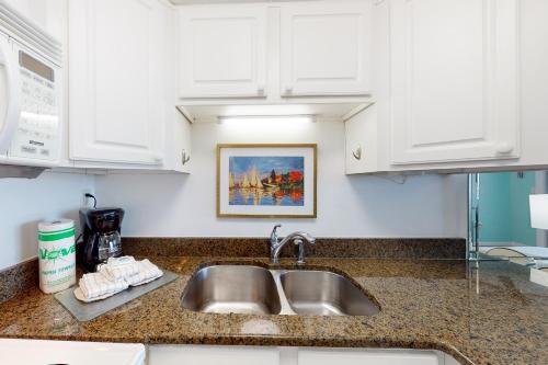 a kitchen counter with a sink and white cabinets at Jetty East A516 in Destin