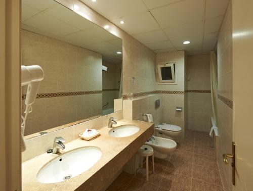 a bathroom with two sinks and a mirror at Hotel Abat Cisneros Montserrat in Montserrat