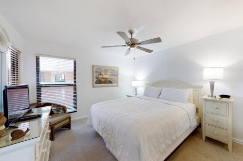 biała sypialnia z łóżkiem i wentylatorem sufitowym w obiekcie Jetty East A516 w mieście Destin