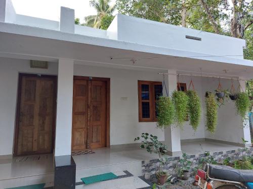 a white house with two doors and potted plants at Nunu Homestay Guruvayoor in Guruvāyūr