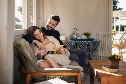 a man and a woman sitting on a couch reading a book at Guadalupe Tuscany Resort in Braccagni