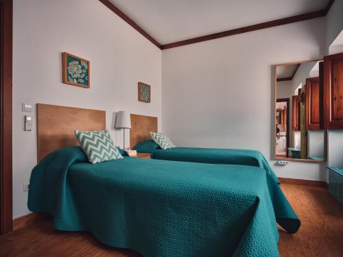 a bedroom with a bed with a green blanket at Quinta Dos Anjos in Santarém