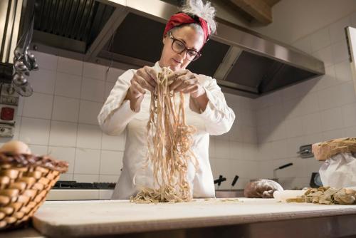 a woman standing in a kitchen preparing food at Guadalupe Tuscany Resort in Braccagni