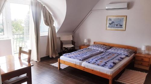 1 dormitorio con cama, mesa y ventana en Zöldház Panzió en Gyenesdiás
