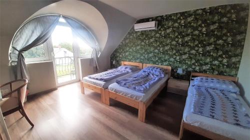 two beds in a room with a wall with flowers at Zöldház Panzió in Gyenesdiás