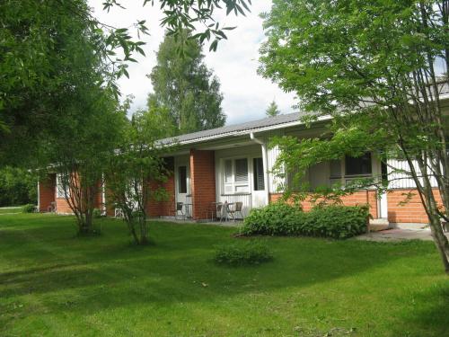 une maison en briques rouges avec une cour verdoyante dans l'établissement Hotelli Ravintola Tiilikka, à Rautavaara