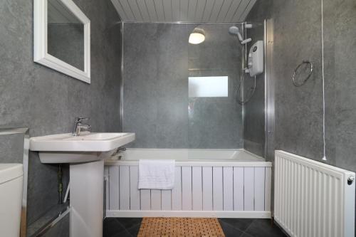 een badkamer met een wastafel, een bad en een douche bij Signature - Carnoustie House in East Kilbride