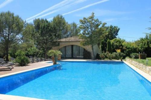 une grande piscine bleue en face d'une maison dans l'établissement Suite de l'olivier au Mas au Coeur de la Provence &SPA, à Saint-Cannat