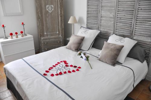 un letto bianco con fiori rossi sopra di Suite de l'olivier au Mas au Coeur de la Provence &SPA a Saint-Cannat