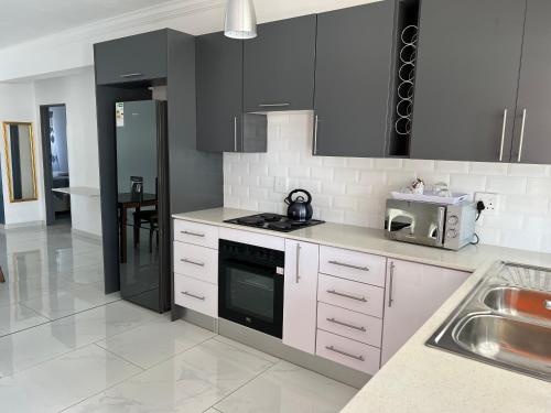 a kitchen with white cabinets and black appliances at Aloe Apartments in Burgersfort