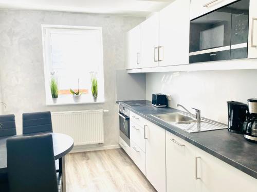 cocina con armarios blancos, fregadero y mesa en Ferienwohnung Appartamento Da Vinci en Eisenach
