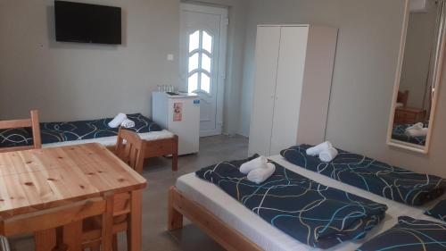 a room with two beds and a table and a television at Zöldház Panzió in Gyenesdiás