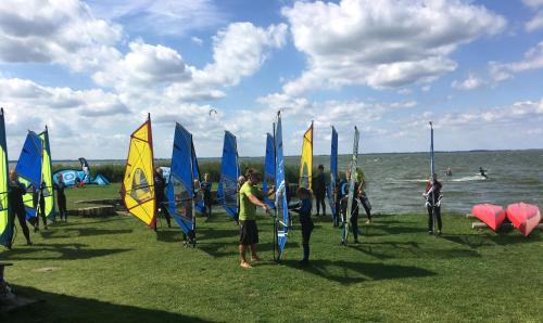a group of people standing in the grass with sails at Pension Café Knatter in Ueckeritz