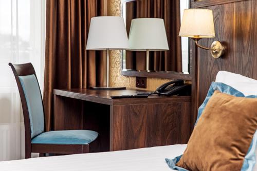 a hotel room with a desk with a bed and a phone at Gradiali Wellness and SPA in Palanga