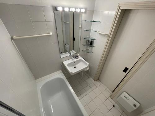 ein weißes Badezimmer mit einem Waschbecken und einer Badewanne in der Unterkunft Villa Gina App 6060 in Brissago