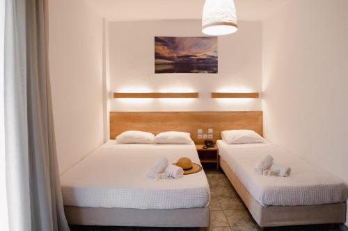 two beds in a room with white walls at Calma Beach Hotel in Stavros