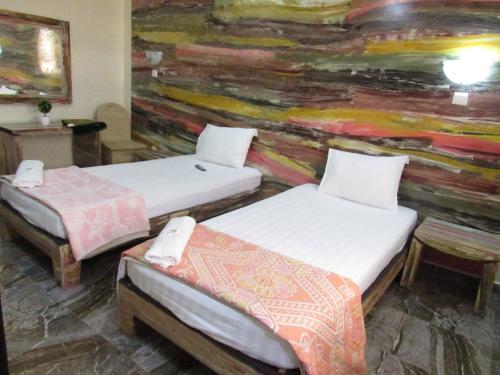 FatickにあるHotel Berges du Sineのベッド2台付きの部屋、壁に絵画が飾られた部屋