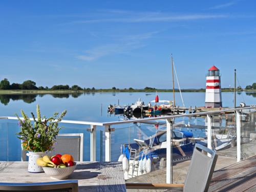 a table with a bowl of fruit on a dock with a boat at Ferienappartement AM LEUCHTTURM in Mursewiek