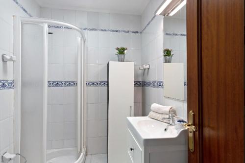 a white bathroom with a shower and a sink at Villa Las Palmeras in Playa Blanca