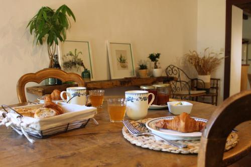 une table avec un petit-déjeuner composé de pain et de jus d'orange dans l'établissement LE DOMAINE DU PETIT TERTRE - SPA EN EXTERIEUR, à Saint-Jean-dʼAssé