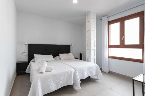 a white bedroom with a bed with two towels on it at Vegueta Luxury Apartments in Las Palmas de Gran Canaria