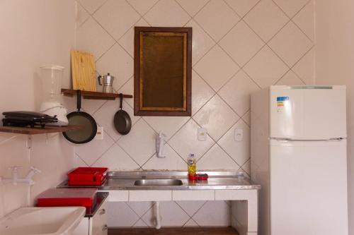 uma cozinha com um lavatório e um frigorífico branco em Casa do Pepe em Cairu