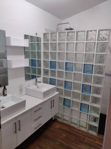 a bathroom with two sinks and glass wall at Agréable maison de village proche de la mer in Bages