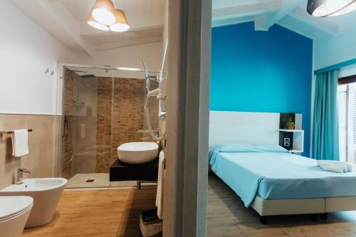 een blauwe slaapkamer met een bed, een bad en een wastafel bij I Ginepri Hotel in Cala Gonone