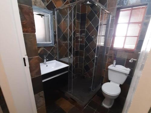 Un baño con inodoro, lavabo y ducha. en La Casa Guest House, en Bloemfontein