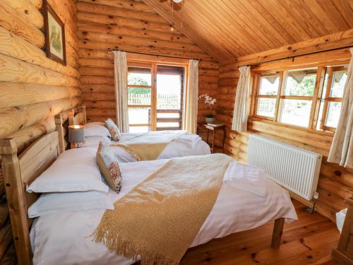 1 dormitorio con 2 camas en una cabaña de madera en Far Coley Farm and Kilnhurst Log Cabin, en Stafford