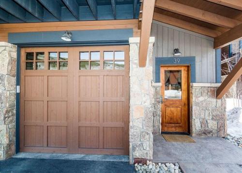 a garage with a brown door and a stone wall at River Run Townhomes by Summit County Mountain Retreats in Keystone