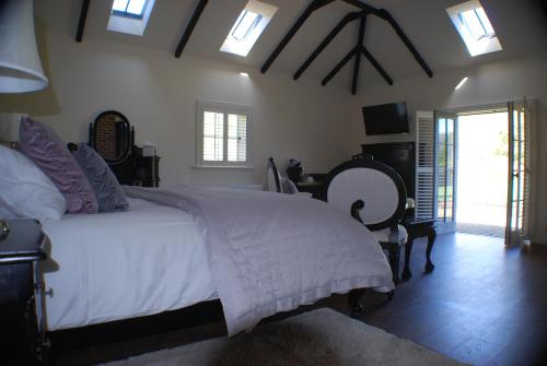 een slaapkamer met een groot bed met witte lakens en ramen bij Clonganny House in Ballygarrett