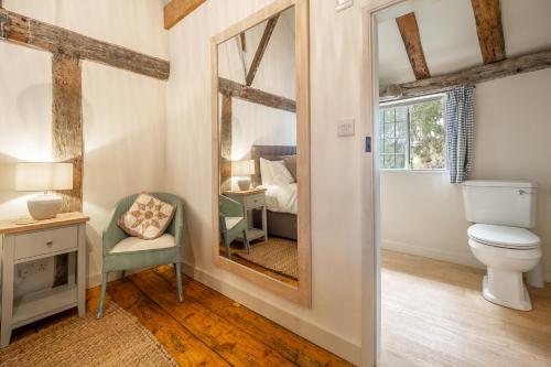 a bathroom with a toilet and a mirror at Angelic 16th Century cottage in key Constable village - Bear Cottage in Nayland