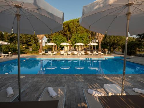 una piscina con sombrillas, sillas y mesas en Santamaria Village Resort Ascea, en Ascea