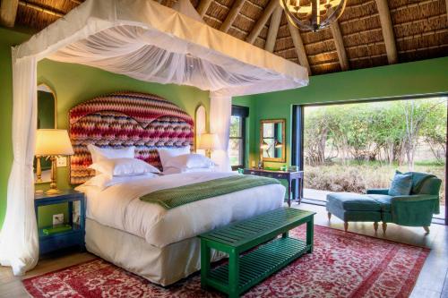 um quarto com uma cama grande e uma janela grande em Royal Malewane em Thornybush Game Reserve