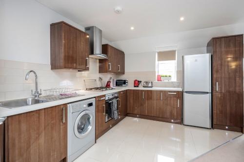 a kitchen with wooden cabinets and a washer and dryer at Roomspace Serviced Apartments - Nevis Court in Surbiton
