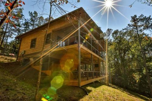 a house with a glass facade in the woods at NEW Modern Cabin! 2 Large Decks, Hot Tub, Sleeps 8 in Ellijay