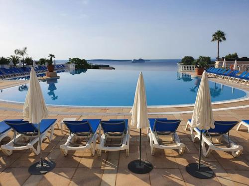 un groupe de chaises et de parasols à côté d'une piscine dans l'établissement Chagall 3 étoiles YourHostHelper, à Cannes