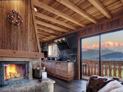a living room with a fireplace and a mountain view at CHALET LES CERISES Jacuzzi, Sauna, Hammam, Cinéma in Cordon