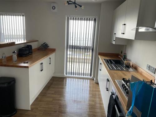 a kitchen with white cabinets and a wooden floor at 2 Plas Morolwg in Aberystwyth