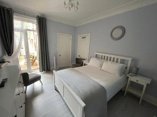 1 dormitorio con cama blanca y reloj en la pared en Kates’s Place en Ulwell