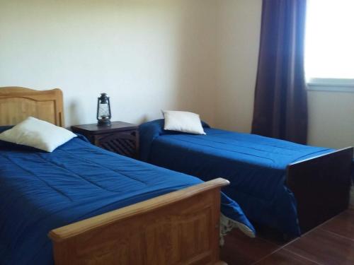 ein Schlafzimmer mit zwei Betten mit blauer Bettwäsche und einem Fenster in der Unterkunft Casa en Villa Los Aromos in La Bolsa