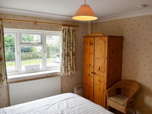 um quarto com uma cama, uma cómoda e uma janela em Blacksmiths Cottage em Gillamoor